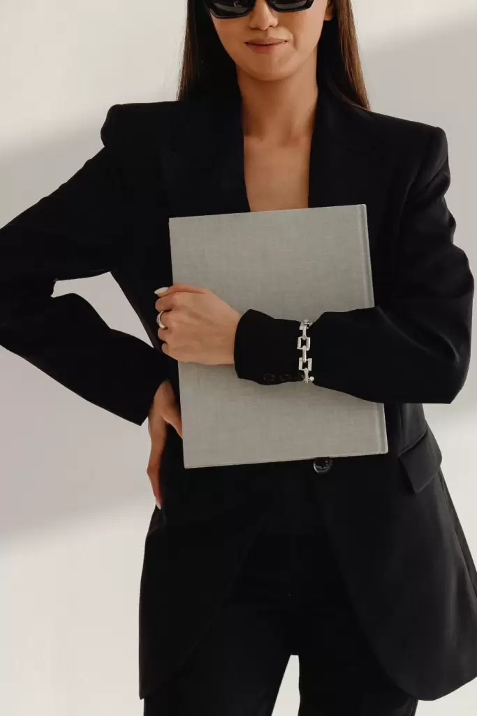 female ai content editor business woman dressed in black holding silver laptop